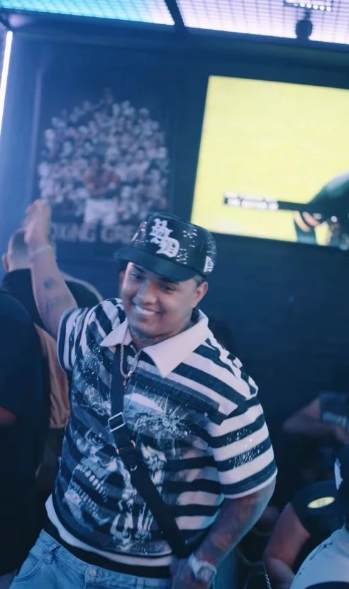 A frame from LMP's reel: a smiling man in a striped shirt and a cap dancing, a hand raised behind him