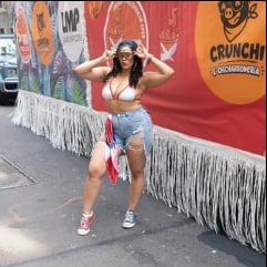 A dancer in front of the float's banner with the LMP, Equis Pica Pollo and Crunchi logos