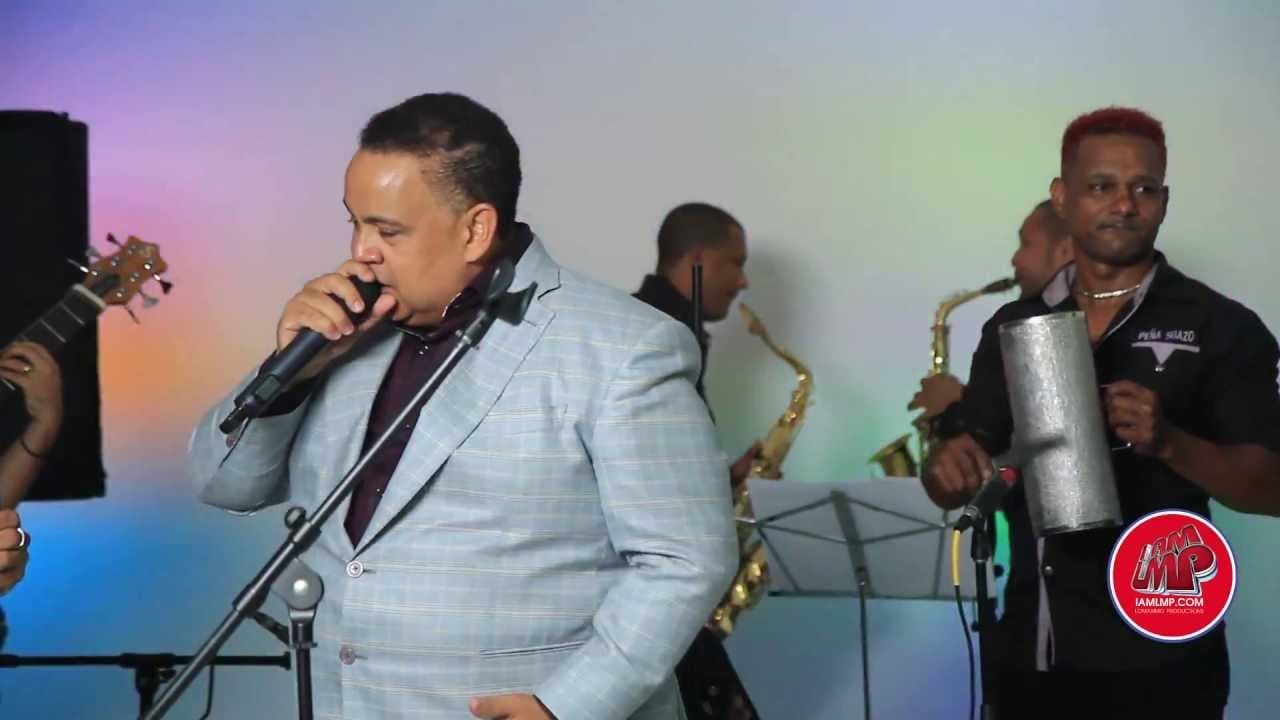 Jose Peña Suazo singing at the mic, horns and percussion behind him