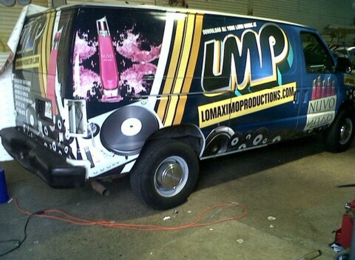 The NUVO-sponsored LMP van from the rear, a pink NUVO bottle and LOMAXIMOPRODUCTIONS.COM on its side