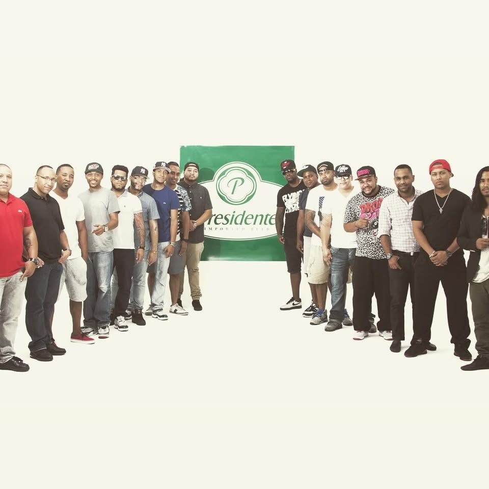 LMP's DJs lined up in front of a Presidente banner