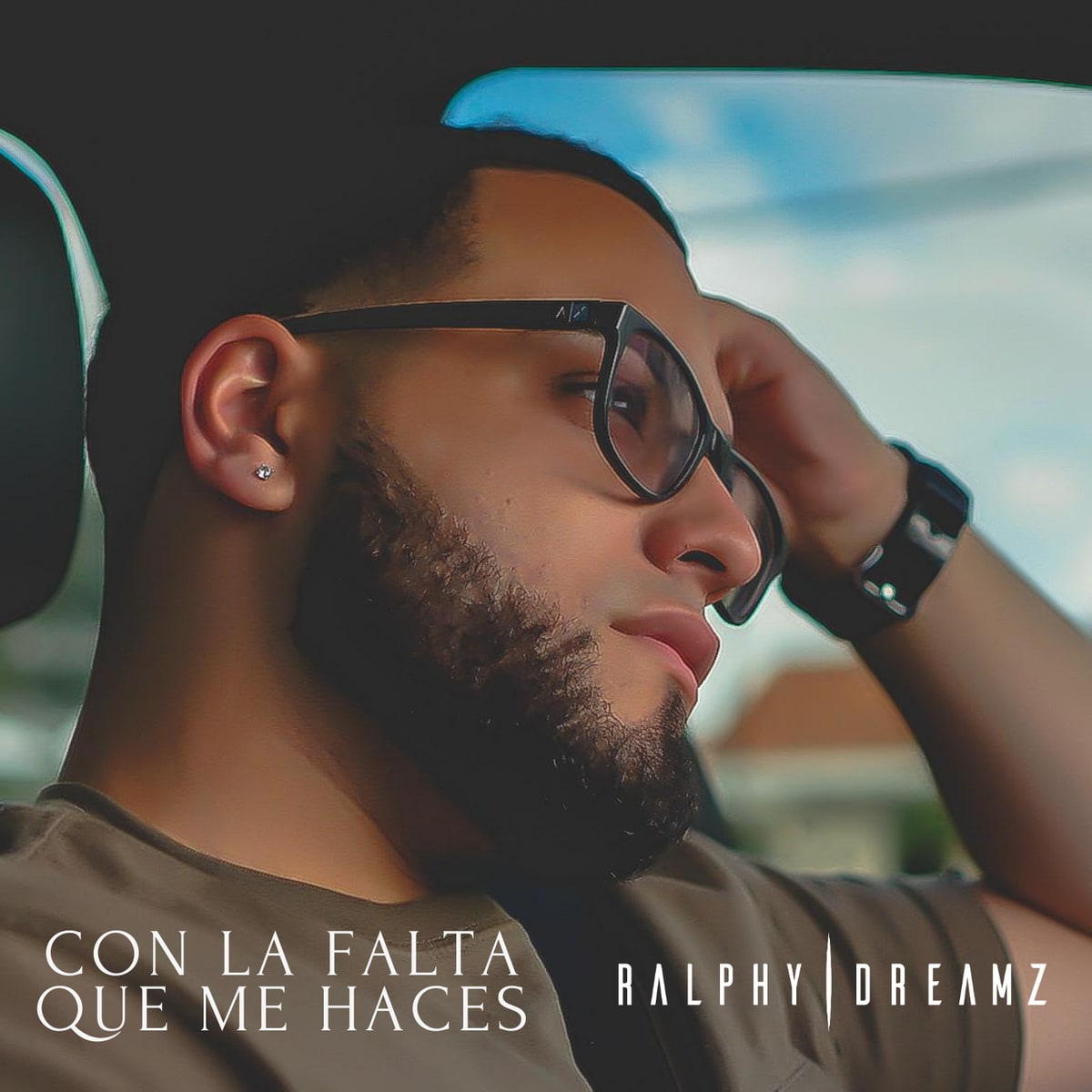 Cover art for Ralphy Dreamz's “Con La Falta Que Me Haces” — the singer in glasses, resting his head on his hand in a car, with the title and “Ralphy | Dreamz”